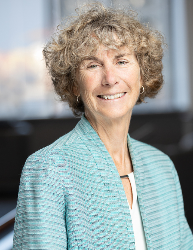 SFU's Nancy Olewiler smiling at the camera wearing a white shirt and a light blue blazer.