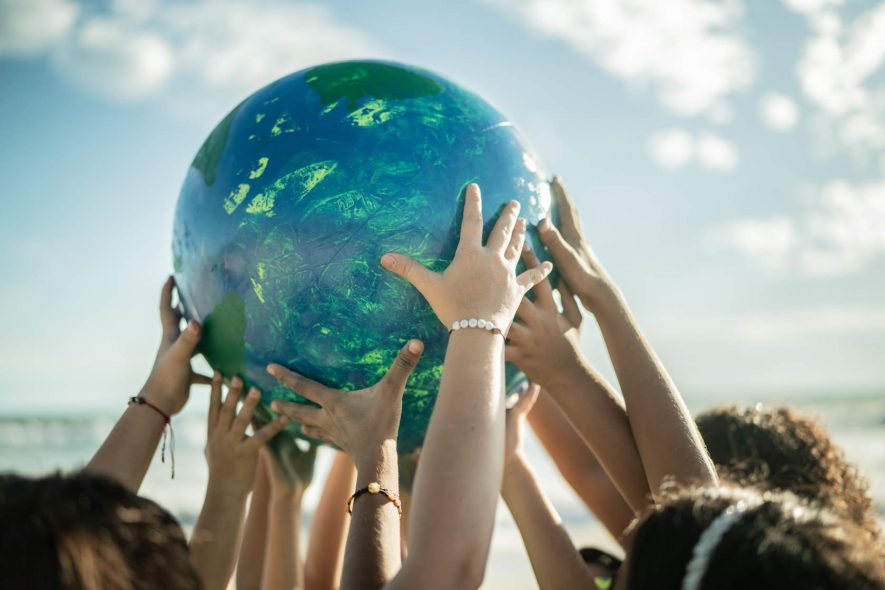 A group of people hold a globe over their heads.