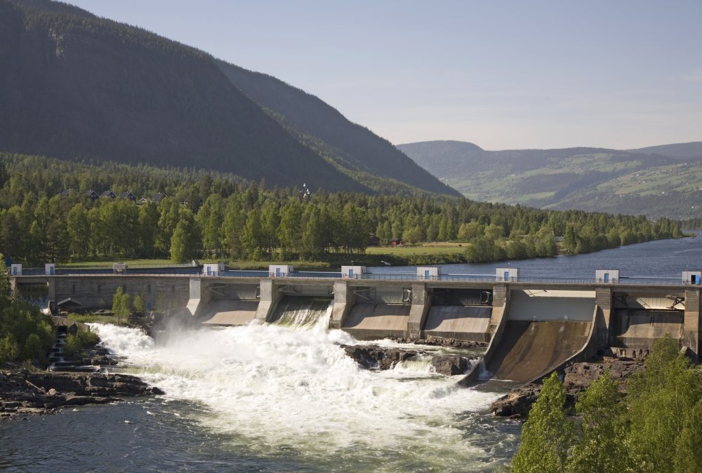 A small dam and power plant in Gudbrandsdal, eastern Norway, surrounded by mountains and forests.