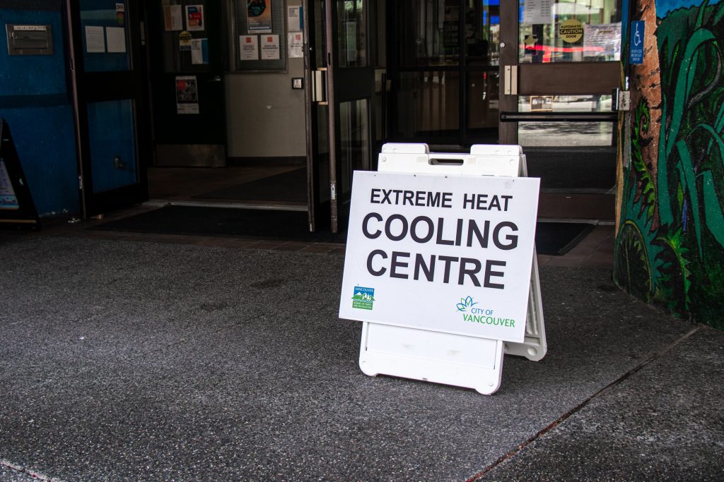 A sandwich board sign outside of what appears to be a community centre with a sign that reads "Extreme heat cooling centre: City of Vancouver" on it.